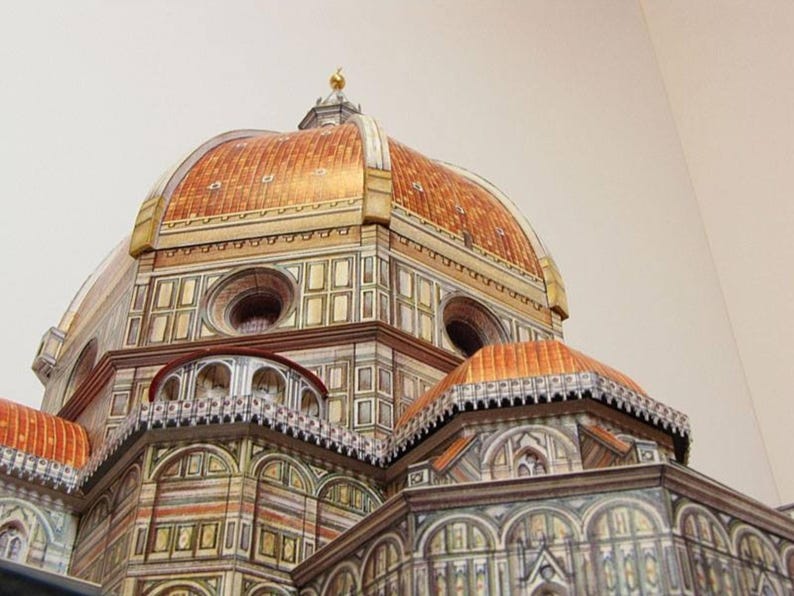 May include: A detailed model of the Duomo in Florence, Italy. The model is made of paper and features intricate details, including the dome, the facade, and the surrounding buildings.