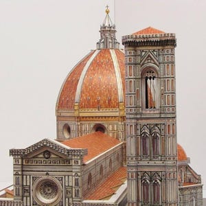 May include: A detailed paper model of the Duomo in Florence, Italy. The model features a red tiled dome, a tall bell tower, and intricate architectural details.