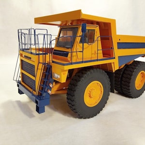 May include: A yellow and blue toy dumper truck with a large cab and a large bed. The truck has a black grille and a black ladder on the side.