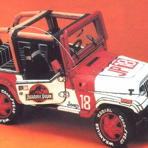 Może przedstawiać: Biały Jeep Wrangler z czerwonymi i czarnymi akcentami. Jeep ma logo "Jurassic Park" na boku i numer "18" na drzwiach. Jeep znajduje się na czerwonym tle.