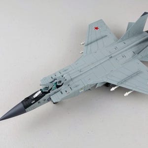 May include: A grey and black model aircraft with red stars on the wings. The plane has a long, pointed nose and swept wings.