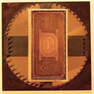 May include: Abstract artwork featuring a rectangular, copper-toned central design with an oval shape, framed within a circular pattern. The artwork incorporates shades of brown, tan, and green, with a textured appearance and rivet-like details around the edges.