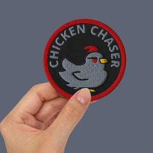 May include: Red and black embroidered patch with the text "Chicken Chaser" and a cartoon chicken with a red comb and yellow beak.