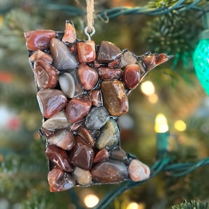May include: A Christmas ornament shaped like the state of Minnesota, made of red, brown, and gray agate stones.
