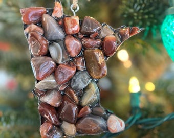 May include: A Christmas ornament shaped like the state of Minnesota, made of red, brown, and gray agate stones.