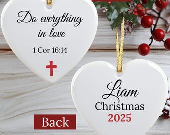 May include: White heart-shaped Christmas ornament with gold ribbon. The front has the text "Do everything in love" and "1 Cor 16:14" with a red cross. The back says "Liam Christmas 2025".