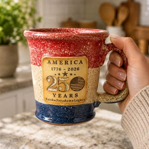 May include: A ceramic mug with a speckled red, white, and blue glaze. A central tan rectangular plaque features the text AMERICA 1776-2026, the number 250, a small American flag icon, and the words YEARS FAITH FREEDOM LEGACY in black lettering.