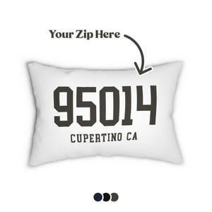 Op de afbeelding: Een rechthoekig wit kussen met de zwarte tekst 95014 en CUPERTINO CA. Boven het kussen staat de tekst Your Zip Here met een gebogen pijl die naar beneden wijst. Daaronder bevinden zich drie kleine cirkelvormige kleurstalen.
