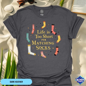 May include: Dark heather grey t-shirt with a graphic of colorful socks and the text "Life is Too Short for Matching Socks".