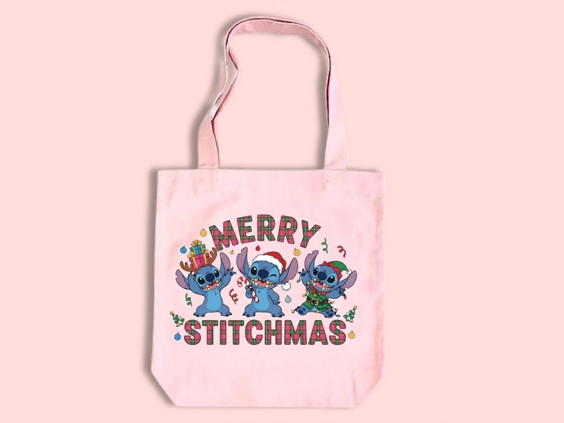 May include: A pale pink tote bag with a festive design. It features three blue cartoon characters and the words "MERRY STITCHMAS" in a plaid pattern, perfect for the Christmas season.
