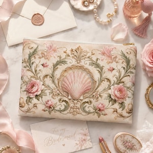 Könnte beinhalten: Eine cremefarbene Kosmetiktasche mit Muscheldesign, umgeben von floralen und Rankenmustern. Die Tasche ist mit rosa Rosen und grünen Blättern verziert. Eine Karte mit der Aufschrift "For my Bridesmaid" ist ebenfalls zu sehen.
