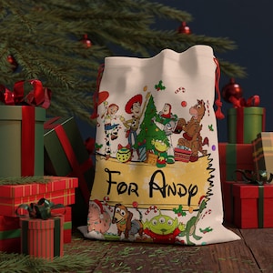Könnte beinhalten: Ein cremefarbener Weihnachtsgeschenkebeutel mit Toy Story-Figuren und dem Text "For Andy". Der Beutel hat einen roten Kordelzugverschluss und ist von verpackten Geschenken und einem Weihnachtsbaum umgeben.