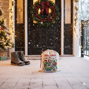 May include: A beige drawstring gift bag with the name "BENJAMIN" printed in red. The bag features a colorful cartoon design of characters. A pair of winter boots and a Christmas wreath are in the background.