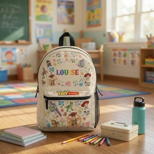 Könnte beinhalten: Ein cremefarbener Rucksack mit einem Toy Story-Aufdruck, der Charaktere wie Woody, Buzz Lightyear und Jessie sowie florale Akzente zeigt. Der Name LOUISE ist in bunten Buchstaben über einer Vordertasche mit einem Toy Story-Logo aufgedruckt.
