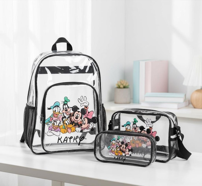 Puede incluir: Un conjunto de mochila, bandolera y estuche transparentes con un dise&ntilde;o de rayas blancas y negras. Cada art&iacute;culo muestra un gr&aacute;fico colorido de personajes de Disney, incluyendo Mickey Mouse, Donald Duck y Goofy. El estuche y la bandolera tienen ribetes negros.