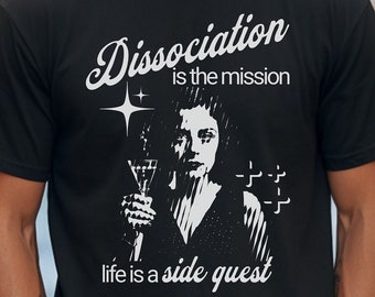 May include: Black t-shirt with a white graphic design. The graphic features a woman holding a glass of wine and the text "Dissociation is the mission life is a side quest".