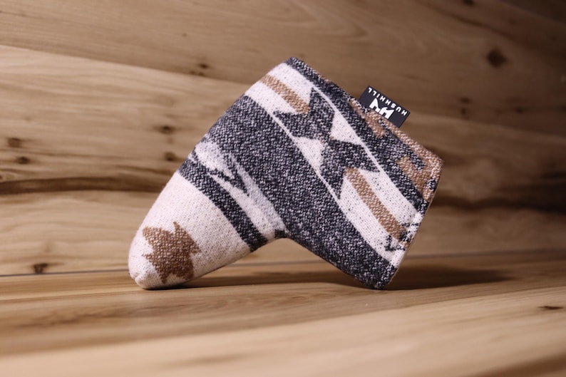 Op de afbeelding: Golfclubhoofdhoes met een geometrisch patroon in cr&egrave;me, zwart en bruin. De hoes heeft een rechthoekige vorm met een afgeronde punt en een klein zwart label met witte tekst. De hoes is gemaakt van een geweven stof.