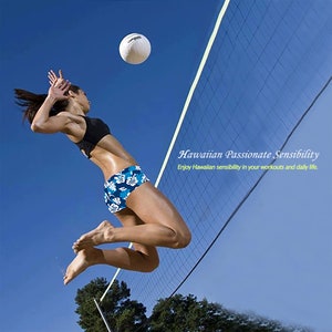 May include: A woman wearing a black sports bra and blue floral print shorts jumps to spike a white volleyball over a net. The background is a bright blue sky. The text "Hawaiian Passionate Sensibility" and "Enjoy Hawaiian sensibility in your workouts and daily life." is displayed in yellow.