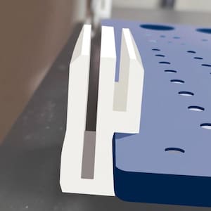 May include: A close-up of a white plastic component with a U-shaped design, next to a blue surface with curved cutouts. The component has a rectangular base and three vertical prongs. The blue surface has several small, curved cutouts.