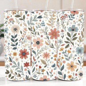 Op de afbeelding: Drie roestvrijstalen bekers met een witte achtergrond en een bloemenpatroon in roze, blauwe en groene tinten. De bekers zijn allemaal even groot en hebben een rietje.