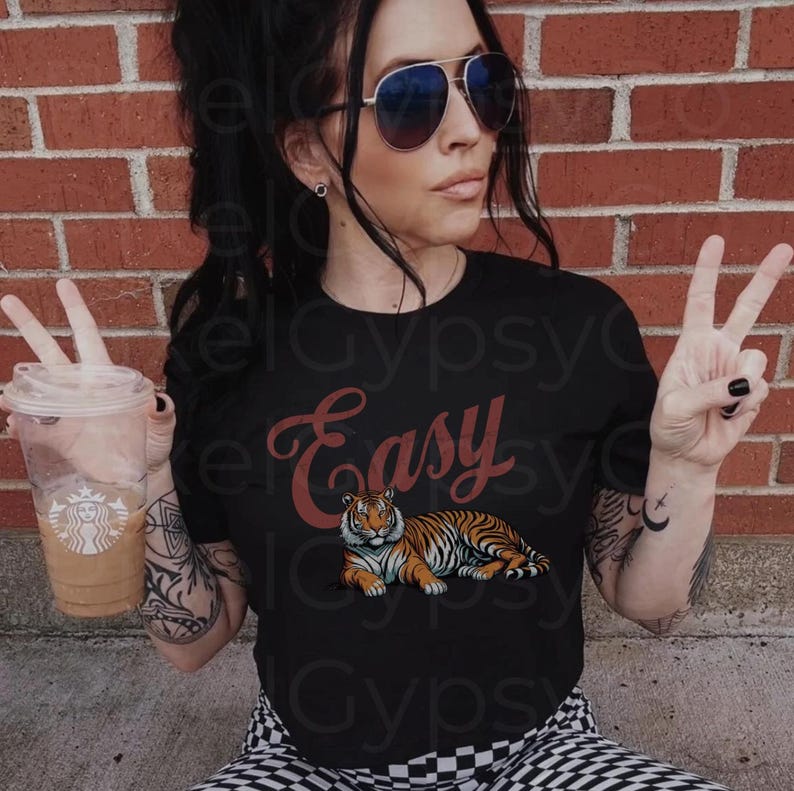 May include: A black t-shirt with the word "Easy" in red cursive lettering and a tiger illustration. The tiger is orange and black with a white background.