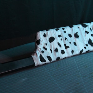 May include: A black and white dalmatian print fabric wrapped around a black knife handle.