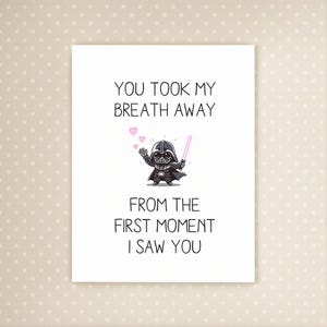 Könnte beinhalten: Weiße Grußkarte mit dem Text "YOU TOOK MY BREATH AWAY FROM THE FIRST MOMENT I SAW YOU". Die Karte zeigt eine Cartoon-Illustration von Darth Vader mit einem Lichtschwert und rosa Herzen.