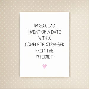 May include: A white card with the text "I'M SO GLAD I WENT ON A DATE WITH A COMPLETE STRANGER FROM THE INTERNET" in black, with a pink heart at the bottom. The background is a light beige with small white polka dots.