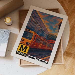 May include: A print featuring a stylized illustration of a yellow and orange Metro train at the South Gosforth station. The print has a white border and includes the text "M Metro South Gosforth". The background features a building and a colorful sky.
