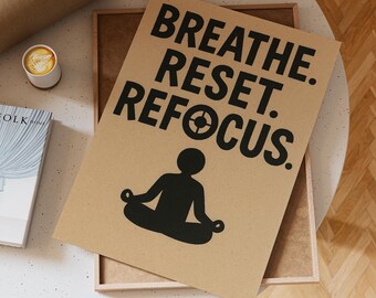 Könnte beinhalten: Ein braunes Poster mit den Worten "Breathe. Reset. Refocus." in großen schwarzen Buchstaben. Eine schwarze Silhouette einer Person in einer sitzenden Yoga-Pose befindet sich unter dem Text. Das Poster befindet sich in einem Holzrahmen auf einem weißen Tisch.