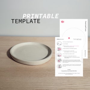 May include: Printable template for building a side plate. The template includes instructions and a diagram of the plate. The template is on a light brown wooden surface. The finished side plate is made of a light gray material and is sitting on the wooden surface.