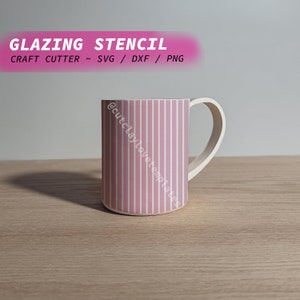 Può includere: Una tazza in ceramica a righe rosa e bianche con un manico. La tazza è su una superficie di legno. Il testo "GLAZING STENCIL" e "CRAFT CUTTER ~ SVG / DXF / PNG" è nella parte superiore dell'immagine. Il testo "@cutclaylovetemplates" è sul lato della tazza.