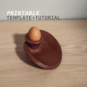 May include: A brown ceramic egg holder with a single brown egg inside. The holder is shaped like a curved plate with a small, raised section for the egg. The holder is sitting on a wooden surface.