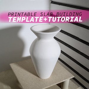 Op de afbeelding: Een witte keramische vaas met een brede opening en een smalle basis, die op een lichtbruine tafel staat. De vaas heeft de vorm van een traditionele urn. De tekst "PRINTABLE SLAB BUILDING TEMPLATE + TUTORIAL" wordt in roze letters bovenaan de afbeelding weergegeven.