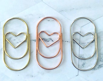 May include: Three heart-shaped paper clips in gold, rose gold, and silver.