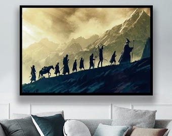 Op de afbeelding: Een ingelijste kunstdruk met een silhouet van een groep figuren die een berg beklimmen. Het kunstwerk toont een dramatische lucht en bergketen op de achtergrond, met een tovenaarachtige figuur op de voorgrond. Het kleurenpalet is een mix van blauw, geel en bruin.