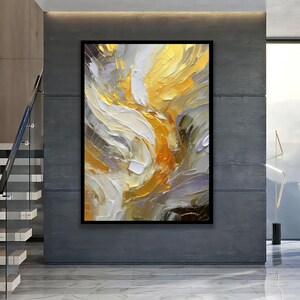 May include: Abstract oil painting in a black frame. The artwork features a textured, swirling design in shades of gold, white, orange, and grey. The brushstrokes are thick and visible, creating a dynamic and energetic composition.