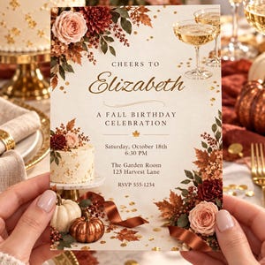 May include: A rectangular birthday invitation card featuring a cream background with floral arrangements of roses and autumn leaves, champagne glasses, a small cake, and pumpkins. Text reads: CHEERS TO Elizabeth A FALL BIRTHDAY CELEBRATION Saturday, October 18th 6:30 PM The Garden Room 123 Harvest Lane RSVP 555-1234.