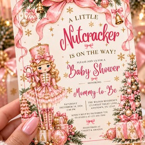 May include: A rectangular baby shower invitation card featuring a pink nutcracker illustration, a large pink bow, and Christmas ornaments. The text reads: A LITTLE Nutcracker IS ON THE WAY! PLEASE JOIN US FOR A Baby Shower HONORING Mommy-to-Be.