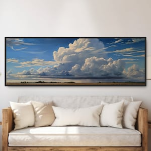May include: A framed landscape painting depicting a large, fluffy white cloud formation against a blue sky. The clouds are casting shadows on a field of green grass in the foreground.