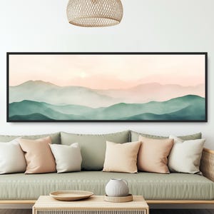 Könnte beinhalten: Ein langer, horizontaler Leinwanddruck mit einer Aquarellmalerei einer nebeligen Bergkette bei Sonnenuntergang. Die Berge sind in Grün- und Rosatönen gemalt, mit einem weichen, ätherischen Schein.