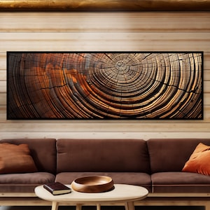 May include: A framed canvas print of a close-up of a tree trunk cross-section. The wood grain is visible in shades of brown, orange, and black. The rings of the tree are visible, showing the age of the tree.