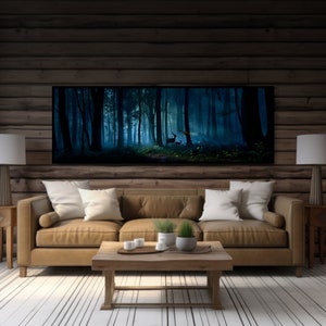 May include: A large framed art print depicting a misty forest scene with deer. The artwork hangs above a tan leather sofa with white pillows. The room has wooden walls and a light-colored wooden floor. Two lamps with white shades flank the sofa.