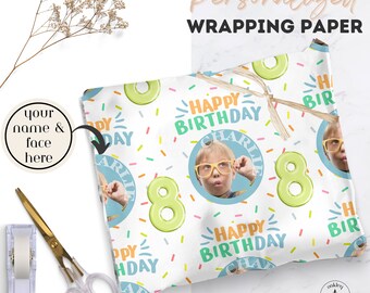 May include: Personalized wrapping paper featuring a repeating pattern of the text Happy Birthday, the number 8 in light green, colorful sprinkles, and a circular photo of a child wearing yellow glasses with the name Charlie printed above it.