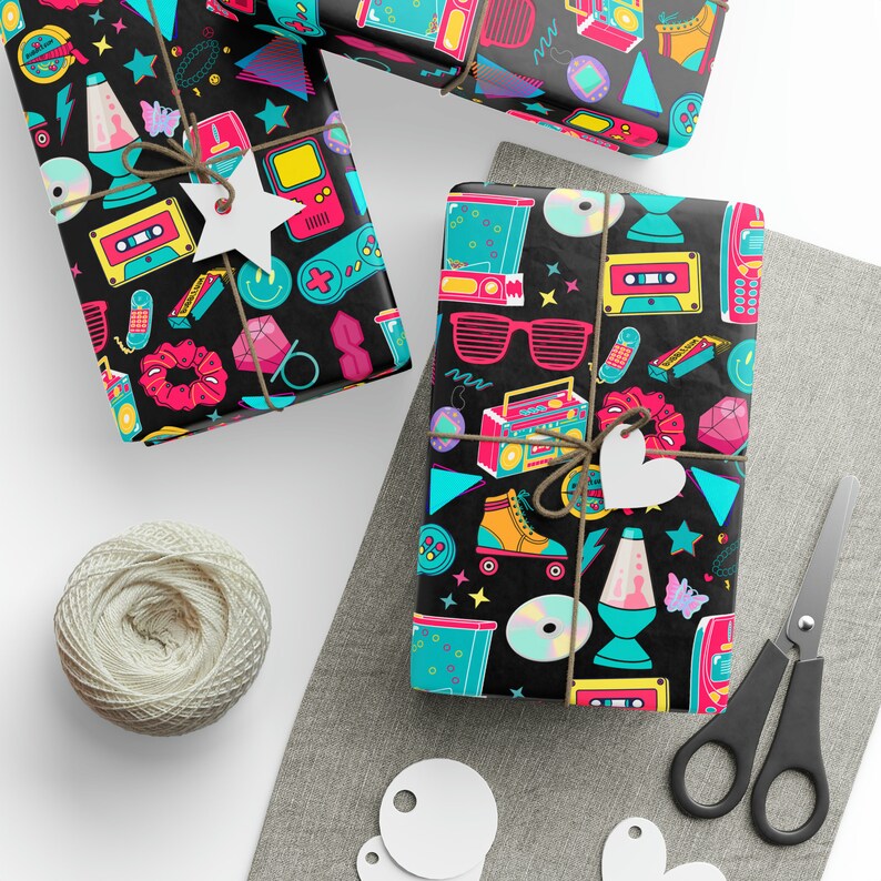 K&ouml;nnte beinhalten: Schwarzes und wei&szlig;es Geschenkpapier mit einem Retro-Thema der 90er Jahre. Das Papier zeigt eine Vielzahl von bunten Symbolen, darunter Kassetten, Rollschuhe, Boomboxen und Lavalampe.
