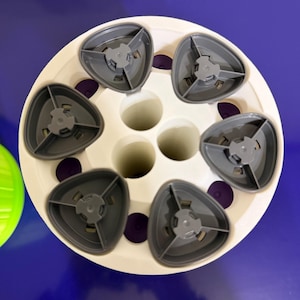 May include: A white ceramic mug with a black handle and the text "But First, Coffee" in a bold, black font. The mug is set against a blurred background, suggesting a cozy setting.