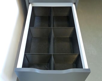 May include: A drawer with six black dividers, creating compartments for organizing items.