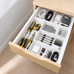 May include: A light wood drawer with white dividers containing organized tools and electronics. Items include screwdrivers, pliers, a utility knife, tape measure, hex keys, charging cables, a USB hub, memory cards, and a white wireless earbud case.