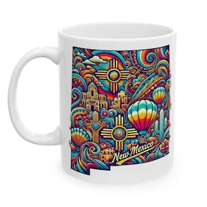 May include: White ceramic mug with a colorful doodle design featuring the state of New Mexico. The design includes hot air balloons, cacti, and the state symbol. The text "New Mexico" is included in the design.