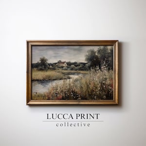 May include: A framed painting of a landscape with a river, trees, and a small house in the distance. The painting is in a gold frame and has a muted color palette.